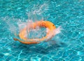 Orange life buoy splash water in the blue swimming pool Royalty Free Stock Photo