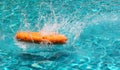 Orange life buoy is splashing with clear blue water in swimming Royalty Free Stock Photo