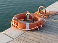 Orange life buoy on wooden pier in the harbor in Marina di Pisa, Tuscany, Italy