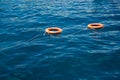 Orange life buoys floating on the surface of blue water