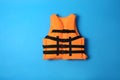 Orange life jacket on blue background. Personal flotation device