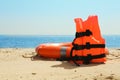 Orange life jacket and buoy on sandy beach near sea. Emergency rescue equipment Royalty Free Stock Photo