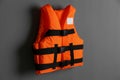 Orange life jacket on grey background. Personal flotation device