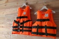 Orange life jackets on wooden background. Personal flotation device