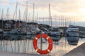 Orange life ring on the pier in the Croatian marina against the backdrop of sailing yachts. Safety on the water and saving drownin Royalty Free Stock Photo