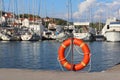 Orange life ring on the pier in the Croatian marina against the backdrop of sailing yachts. Safety on the water and saving drownin Royalty Free Stock Photo