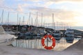 Orange life ring on the pier in the Croatian marina against the backdrop of sailing yachts. Safety on the water and saving drownin Royalty Free Stock Photo