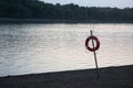 Orange life saver on the beach near the river. Evening landscape Royalty Free Stock Photo