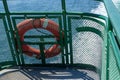 Orange life saving ring hanging on edge of a ship railing Royalty Free Stock Photo