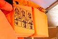 Orange life vests on a ship, closeup on the use instructions, detail How to put on, putting on a life jacket, shallow dof