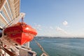 Orange Lifeboat Hanging from Ship Over Blue Sea Royalty Free Stock Photo