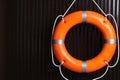 Orange lifebuoy on dark wooden background, space for text. Rescue equipment Royalty Free Stock Photo