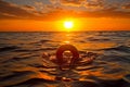 Orange lifebuoy floating in open sea with sunset. Rescue, safety and copy space concept Royalty Free Stock Photo