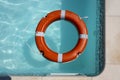 Orange lifebuoy floating on the surface of blue water in a pool Royalty Free Stock Photo