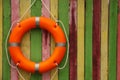 Orange lifebuoy hanging on color wooden fence, space for text. Rescue equipment Royalty Free Stock Photo