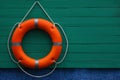 Orange lifebuoy hanging on green wooden board, space for text. Rescue equipment Royalty Free Stock Photo