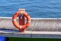 Orange lifebuoy hanging on post at sea boat dock with waves