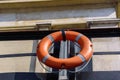 Orange lifebuoy hanging on a rope on a metal fence