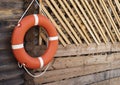 Orange lifebuoy hanging on rope on wooden wall Royalty Free Stock Photo