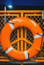 Orange lifebuoy hanging on a safety guardrail of a ferry boat at night sea Royalty Free Stock Photo