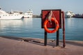 Orange lifebuoy on the pier on the background of yachts near the sea. Safety on the water and rescue from drowning.
