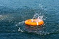 Orange lifebuoy in the sea. The rescue ring fell with a splash on the surface of the water, motion blur .