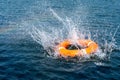 Orange lifebuoy in the sea. The rescue ring fell with a splash on the surface of the water, motion blur .