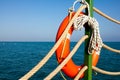 Orange lifeline and sea ropes on the background of the sea and blue sky. Marine ropes and life preserver hanging on a green post o Royalty Free Stock Photo