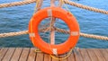 Orange lifeline and sea ropes on the background of the sea and blue sky. Marine ropes and life preserver hanging on a