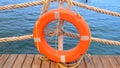 Orange lifeline and sea ropes on the background of the sea and blue sky. Marine ropes and life preserver hanging on a Royalty Free Stock Photo