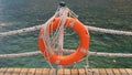 Orange lifeline and sea ropes on the background of the sea and blue sky. Marine ropes and life preserver hanging on a Royalty Free Stock Photo