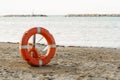 Orange lifesaver, life buoy or rescue buoy on sandy beach Royalty Free Stock Photo