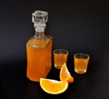 Orange liqueur, strong homemade alcohol and pieces of ripe cut citrus on a black background Royalty Free Stock Photo