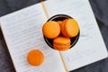 Orange macaroon upon open diary