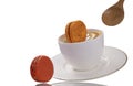 Orange macaroons falling into a cup of coffee