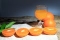 Orange mandarin or tangerine fruits, with green leaves and oranges juices in glass on wooden board background. Royalty Free Stock Photo