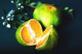 Orange Mandarines, Clementines, Tangerines or small oranges with cut in half with leaves on green background