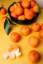 Orange mandarins clementine with green leaves in black plate on a yellow background Royalty Free Stock Photo