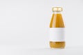 Orange mango juice in glass bottle with gold cap and white blank label mock up on white background with copy space, template. Royalty Free Stock Photo