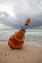An orange marine buoy unmoored and washed up on a beach after a hurricane.