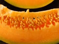 An orange melon slice on black background