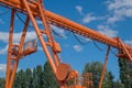 Orange metal single-girder overhead crane with round beam cross-section, electrically driven, cab with hook on two supports. Royalty Free Stock Photo