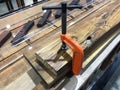 Orange metal wood clamp is holding wood work piece