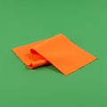Orange microfiber cloth folded neatly on a green surface. The cloth has a soft texture Royalty Free Stock Photo
