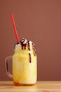 Orange milkshake with chocolate pouring. banan milkshake dessert with orange pasta on wooden table Royalty Free Stock Photo