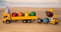 Orange models of toy excavator and dump trucks with Easter quail eggs painted with rainbow colors