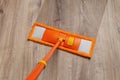 Orange mop washing dusty floor at home. Cleaning the wooden laminate floor with wet microfiber mop. Mopping the floor.