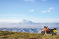 Orange motorbike standing in the fields on the background of mountain range with snow-capped peak