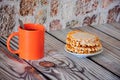 An orange mug of black coffee and a plate with flat waffles and white syrup