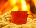 Orange mug for tea or coffee, wool things near cozy fireplace, w